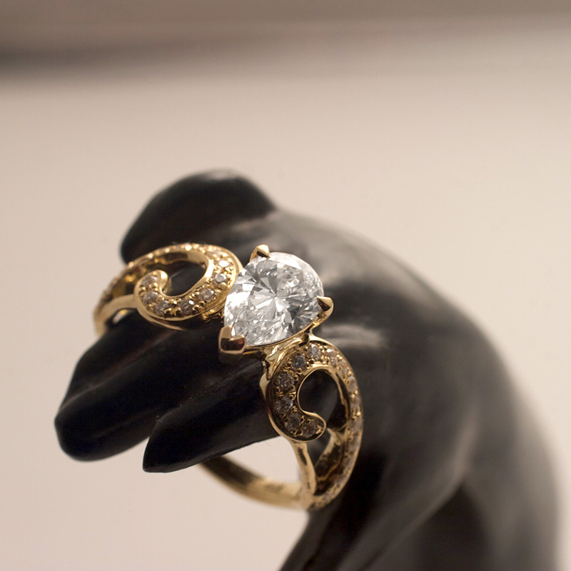アラベスクの枠にパヴェを施した婚約指輪、センターはペアシェープダイヤモンド
